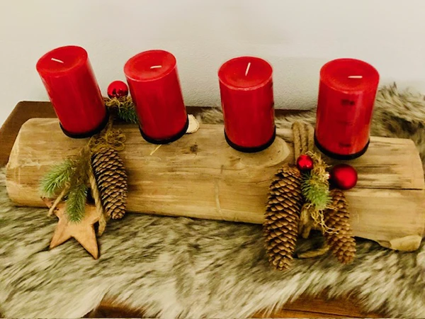 Weihnachtliches Gesteck auf Holz mit Christbaumkugeln und roten Kerzen