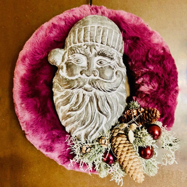 Pinker weihnachtlicher Dekokranz für die Wand mit einem Kopf des Weihnachtsmanns in der Mitte und Christbaumkugeln