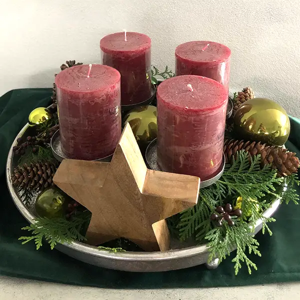 Adventsgesteck mit vier roten Kerzen, Tannenzweigen und Holzstern