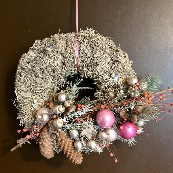 Dekorativer Türkranz mit Tannenzweigen, Zapfen und rosa Weihnachtskugeln