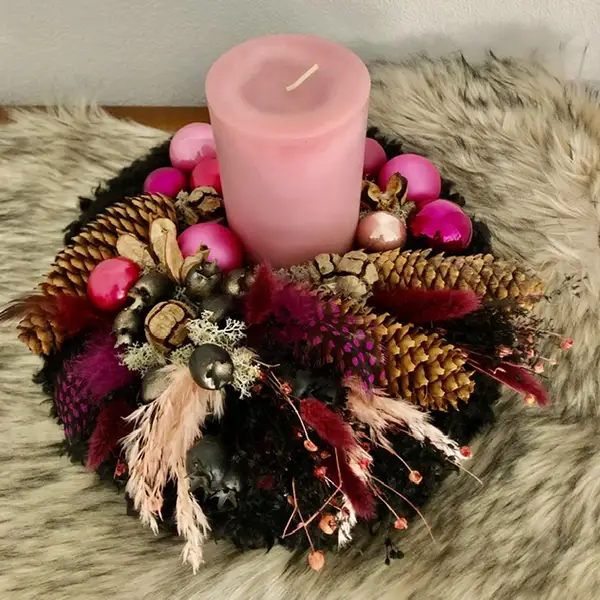 Winterliches Kerzengesteck in Rosa und Pink mit Zapfen und Trockenblumen