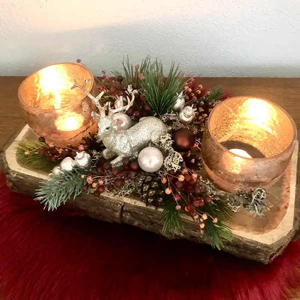 Weihnachtliche Tischdekoration mit zwei Windlichtern, Tannenzweigen und Rentierfigur