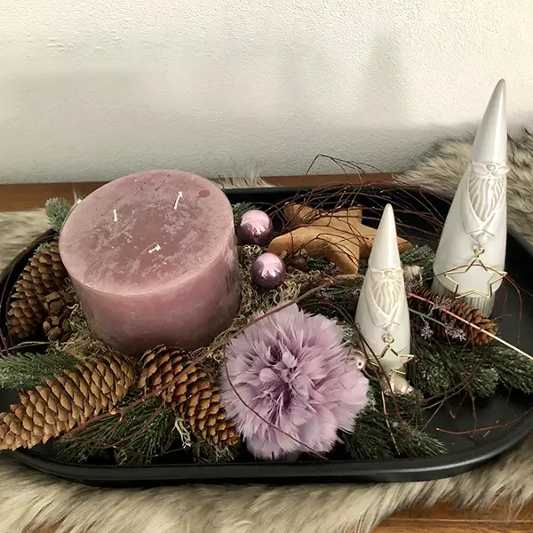 Winterliches Tablett mit rosa Kerze, Zapfen und weißen Dekorationsfiguren
