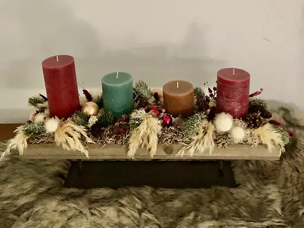 Adventsgesteck mit vier verschiedenfarbigen Kerzen und Naturmaterialien